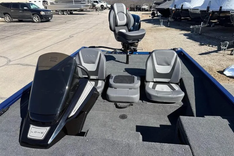 Slide: The Image of 2026 Lowe Stinger 175C boat interior with seating and console, parked outdoors. - 11
