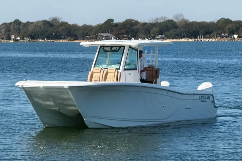 Slide: The Image of 2026 Caymas 30 CT boat cruising on a calm lake with wooded shoreline. - 2