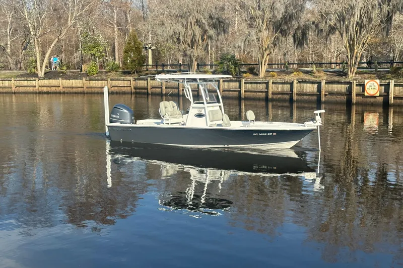 Slide: The Image of 2020 Sportsman Masters 247 Bay Boat on calm river, surrounded by trees. - 7