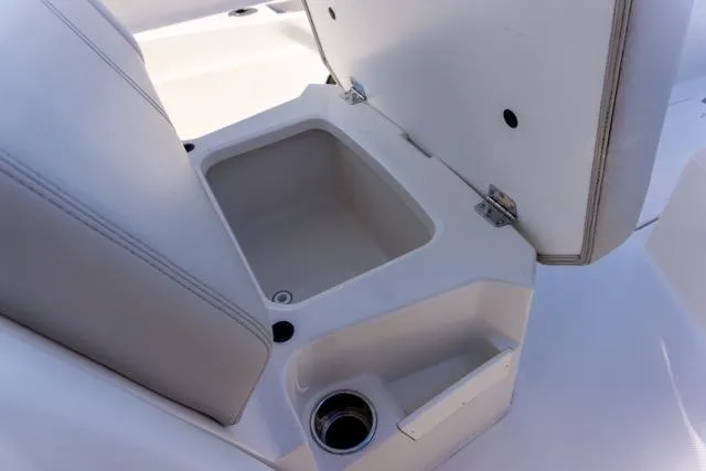 Slide: The Image of 2024 Sailfish 312 CC boat seat storage compartment with cup holder, open lid. - 35