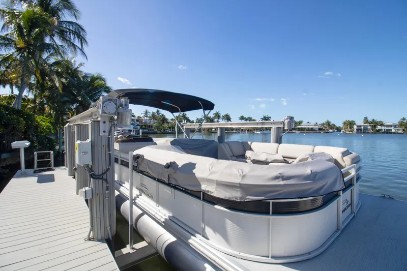 The Image of 2017 Bennington R 28 RSRX1 pontoon boat docked by tropical waterfront. - 0