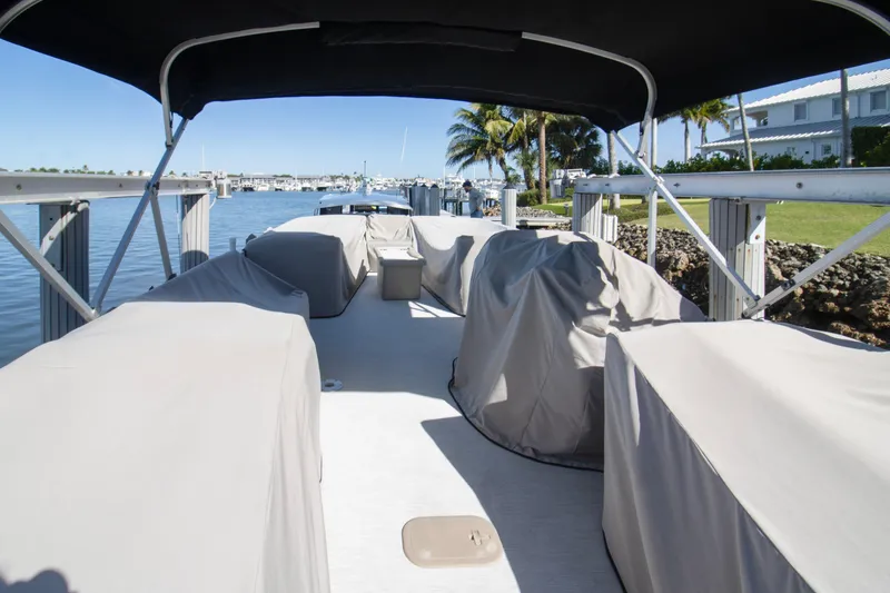 Slide: The Image of 2017 Bennington R 28 RSRX1 pontoon boat docked, covered, with scenic waterfront view. - 2