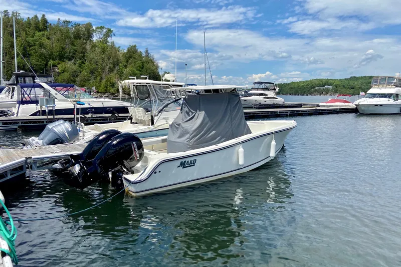 Slide: The Image of 2019 Mako 234 Center Console boat docked at marina, surrounded by other boats. - 1
