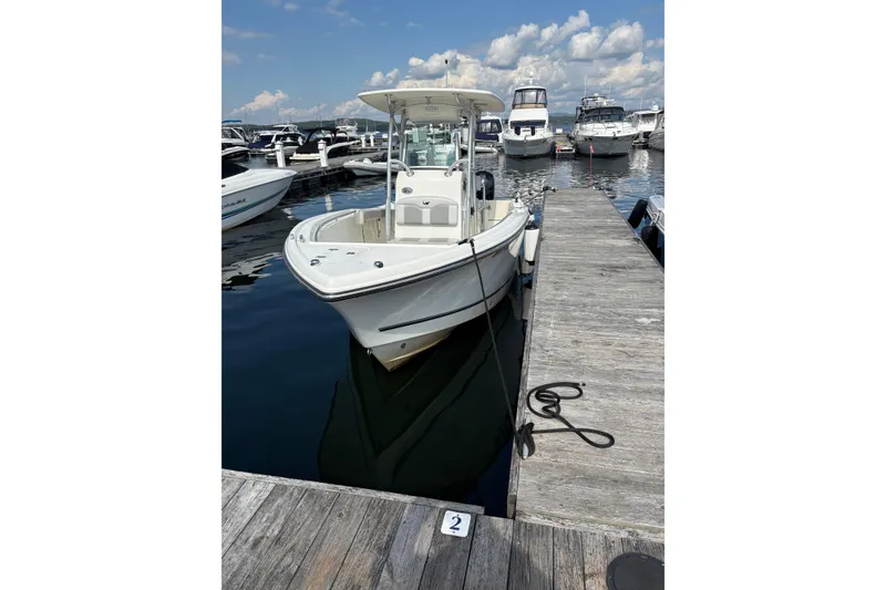 Slide: The Image of 2019 Mako 234 Center Console boat docked at marina under blue sky. - 2