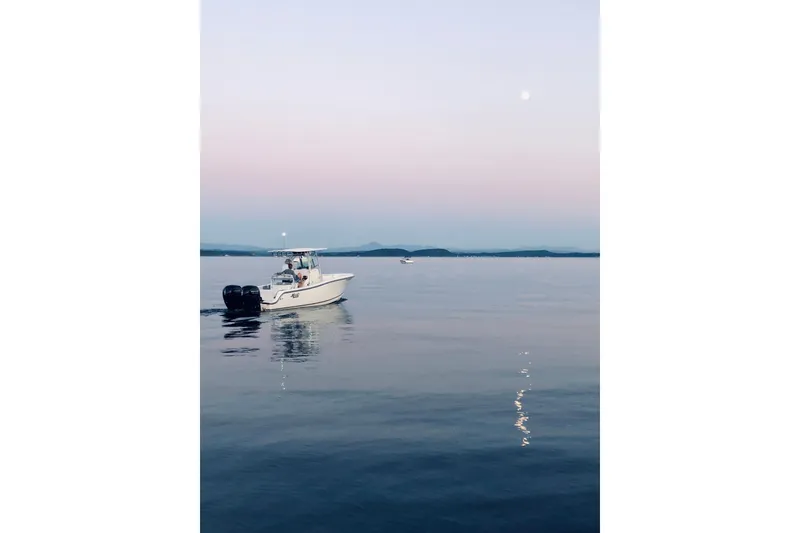 Slide: The Image of 2019 Mako 234 Center Console boat on calm water at sunset. - 4