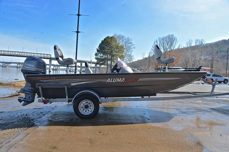 Slide: The Image of 2020 Alumacraft Prowler 175 boat on trailer by riverside, featuring Yamaha outboard motor. - 15