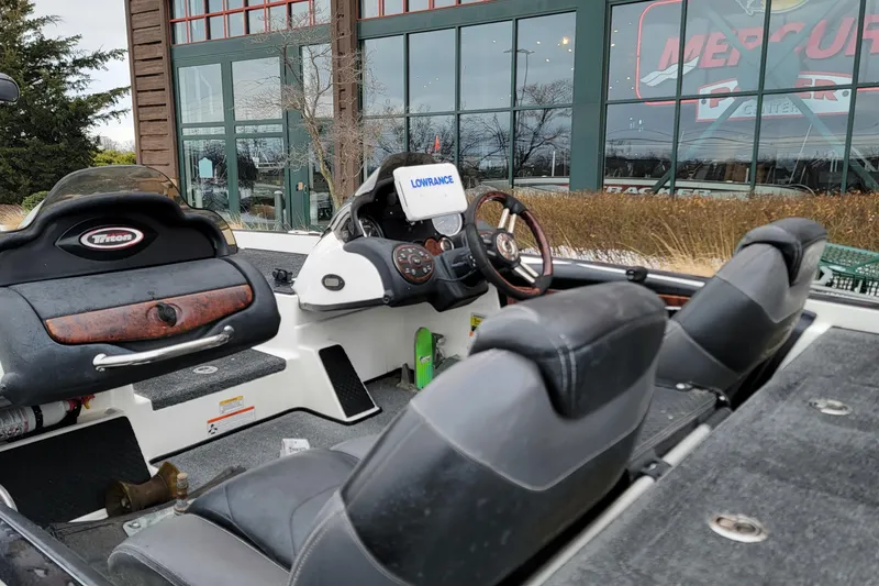 Slide: The Image of 2010 Triton 20XS DC boat interior with steering wheel and seats, parked outside a showroom. - 9