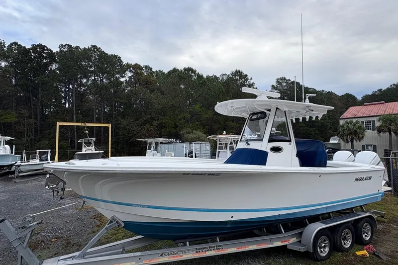 Slide: The Image of 2021 Regulator 28 Forward Seating boat on trailer, surrounded by trees and other boats. - 10