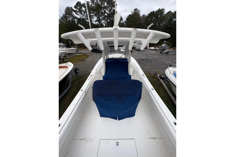 Slide: The Image of 2021 Regulator 28 Forward Seating boat with blue covers, parked outdoors. - 4