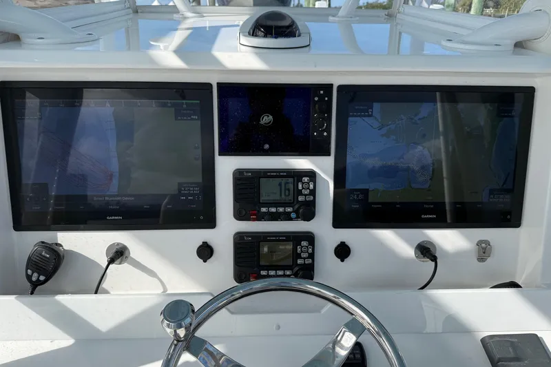 Slide: The Image of 2021 Invincible 36 CC boat dashboard with Garmin navigation displays and controls. - 2