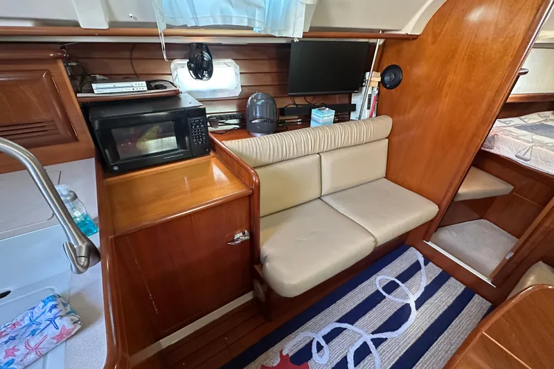 Slide: The Image of Interior of 2001 Beneteau 381 sailboat with seating, microwave, and nautical decor. - 19