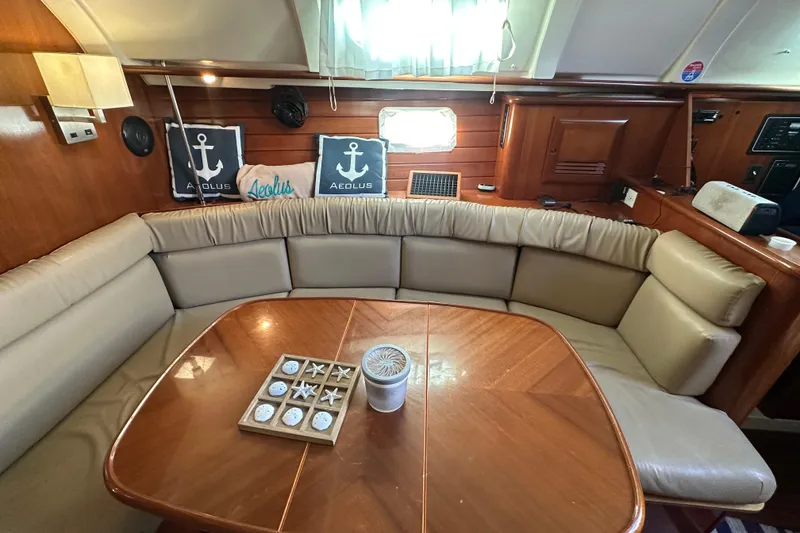 Slide: The Image of Interior of 2001 Beneteau 381 yacht with cushioned seating and wooden table. - 20