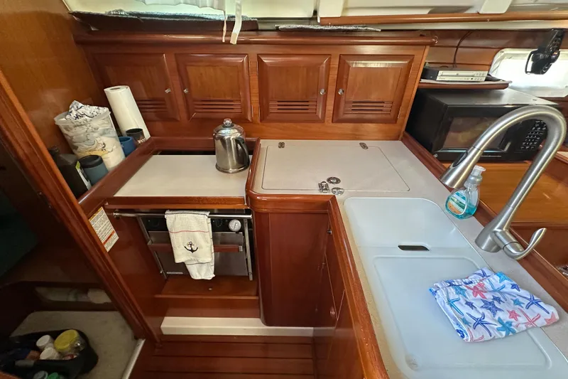 Slide: The Image of 2001 Beneteau 381 yacht kitchen with wooden cabinets, sink, and stove. - 22