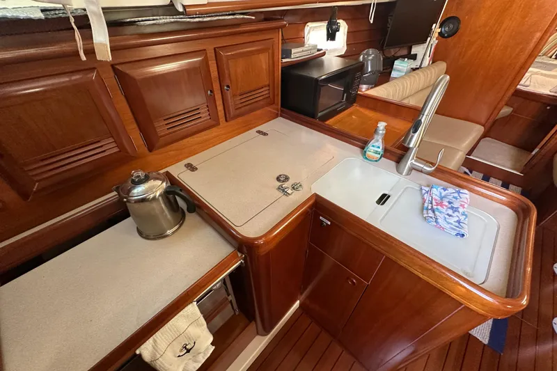Slide: The Image of 2001 Beneteau 381 yacht interior kitchen with wooden cabinetry and modern amenities. - 23
