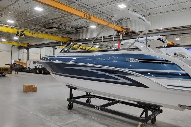 Slide: The Image of 2026 Formula 240 Bowrider boat in a warehouse, blue and white design. - 3