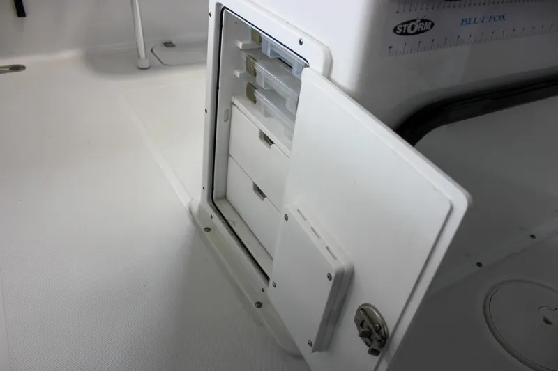 Slide: The Image of 2022 Sea Hunt Gamefish 25 boat storage compartment with open door and organized drawers. - 29
