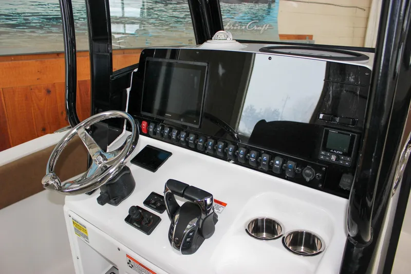 Slide: The Image of 2022 Sea Hunt Gamefish 25 dashboard with steering wheel and electronic controls. - 35