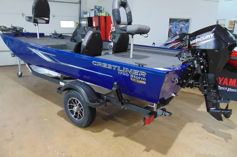 The Image of 2026 Crestliner 1700 Storm boat with Mercury engine, displayed indoors on a trailer. - 1