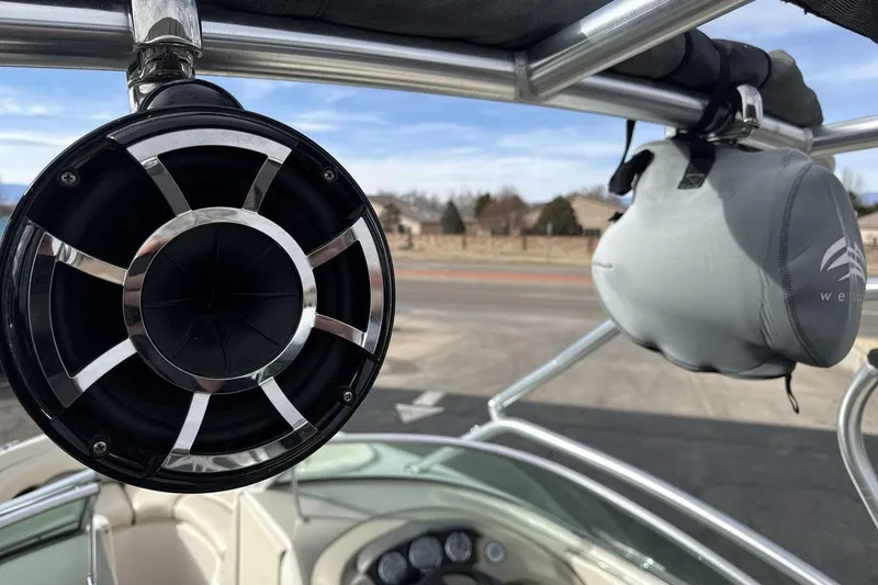 Slide: The Image of 2004 Sea Ray 220 Select boat with speaker and wakeboard tower, clear sky background. - 21