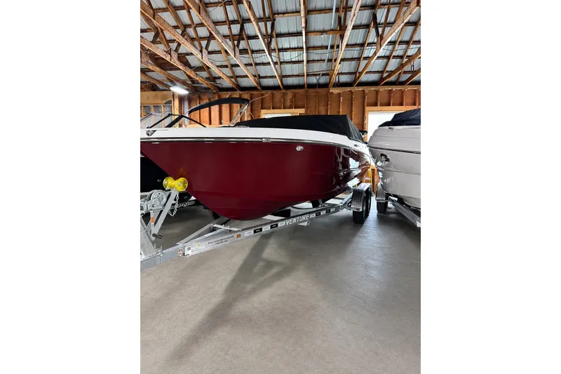 The Image of 2026 Stingray 20 SBX boat in storage, red hull, on trailer, indoor facility. - 0