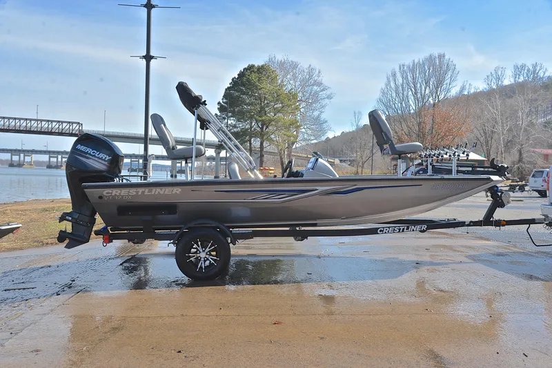 Slide: The Image of 2017 Crestliner VT 17 boat on trailer by a lakeside, featuring a Mercury outboard motor. - 15