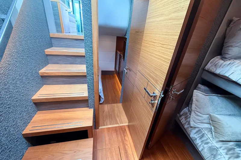 Slide: The Image of Interior of 2019 Tiara Yachts F53 Flybridge, featuring wooden stairs and cozy bunk beds. - 101