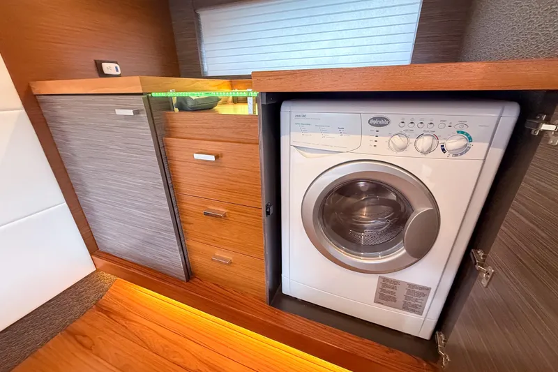 Slide: The Image of Laundry area with washer in 2019 Tiara Yachts F53 Flybridge, featuring wood cabinetry. - 104