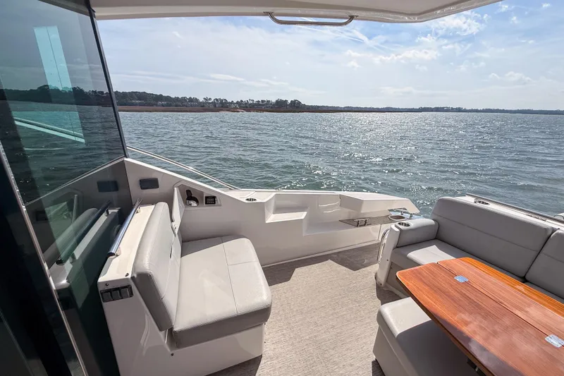 Slide: The Image of 2019 Tiara Yachts F53 Flybridge interior with ocean view, featuring comfortable seating and wooden table. - 43