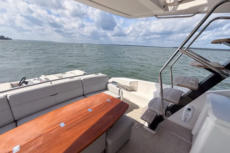 Slide: The Image of 2019 Tiara Yachts F53 Flybridge, elegant deck view with wooden table and ocean backdrop. - 44
