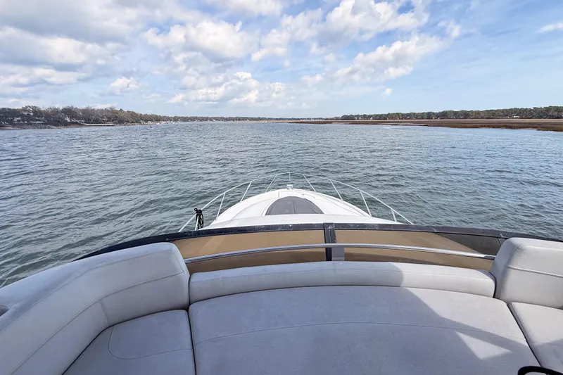Slide: The Image of 2019 Tiara Yachts F53 Flybridge cruising on a serene waterway under a partly cloudy sky. - 48