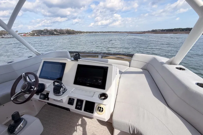 Slide: The Image of 2019 Tiara Yachts F53 Flybridge helm with dual screens, steering wheel, and water view. - 50