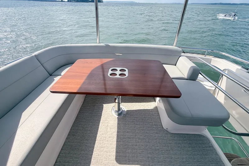 Slide: The Image of 2019 Tiara Yachts F53 Flybridge with elegant seating and wooden table on deck. - 51