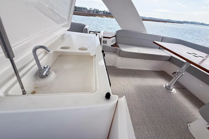 Slide: The Image of 2019 Tiara Yachts F53 Flybridge interior with sink, seating, and table overlooking water. - 54