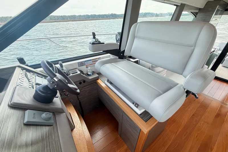 Slide: The Image of 2019 Tiara Yachts F53 Flybridge helm with leather seat and steering wheel, overlooking water. - 80