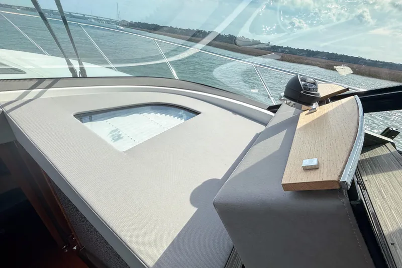 Slide: The Image of 2019 Tiara Yachts F53 Flybridge helm with compass, overlooking serene waters. - 86