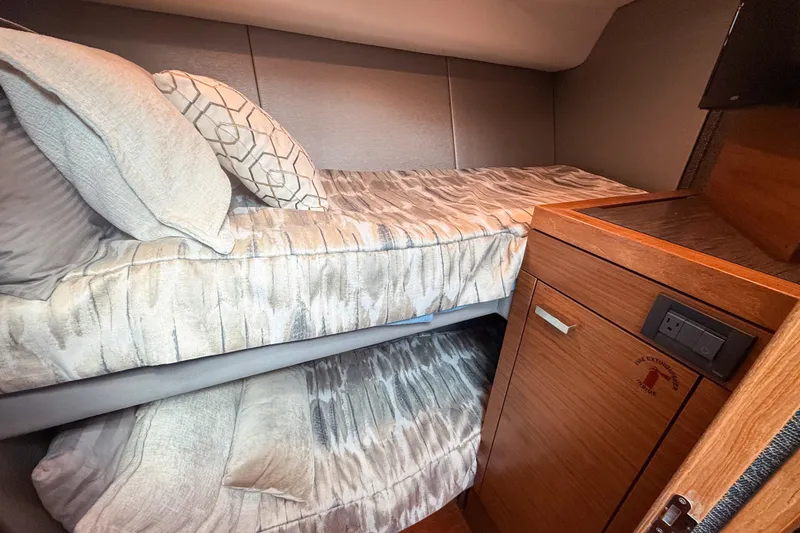 Slide: The Image of 2019 Tiara Yachts F53 Flybridge cabin with cozy bunk beds and wooden cabinetry. - 91