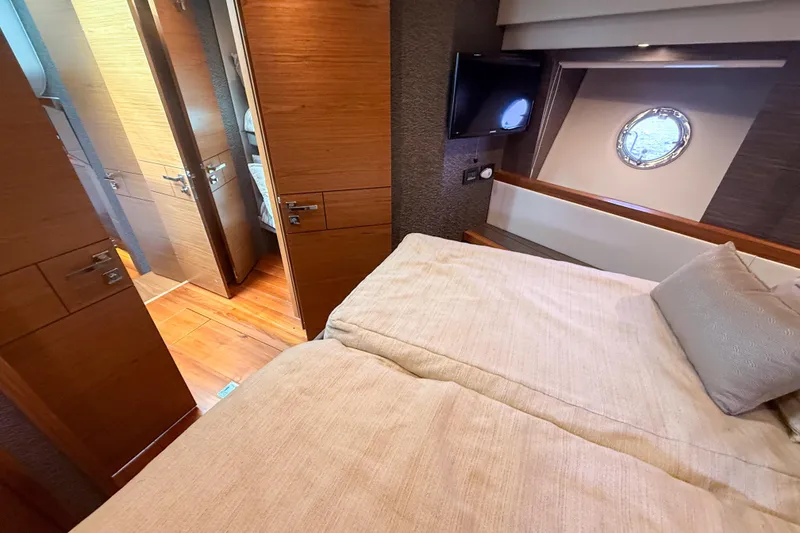 Slide: The Image of Luxurious bedroom interior of 2019 Tiara Yachts F53 Flybridge with wood accents and porthole window. - 94