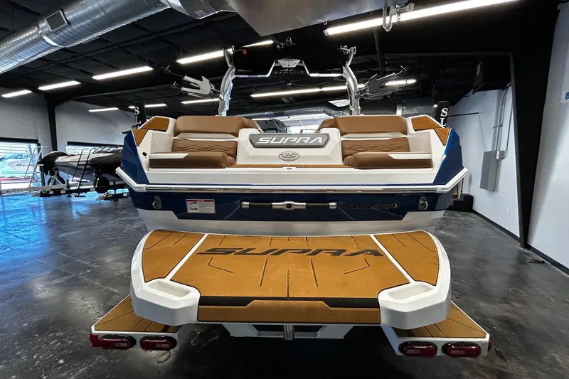 Slide: The Image of 2025 Supra SA boat in showroom, featuring sleek design and comfortable seating. - 2