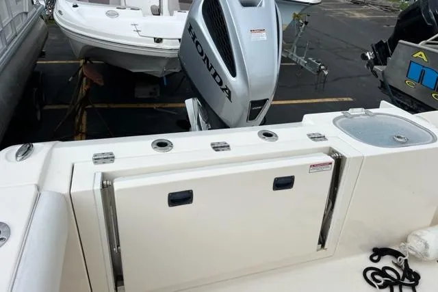 Slide: The Image of 2021 Cobia 237 Center Console boat with Honda outboard motor in a marina. - 2