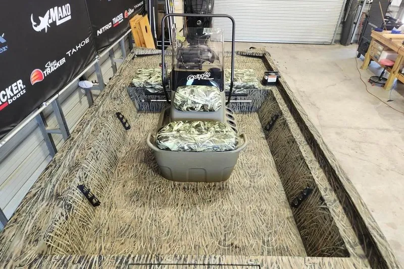 Slide: The Image of 2025 Tracker Grizzly 1860 CC boat with camouflage interior in a workshop setting. - 9