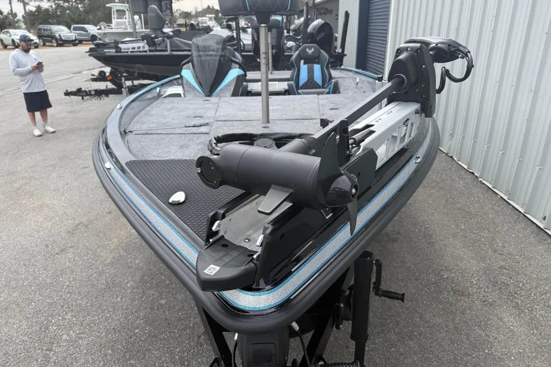 Slide: The Image of 2026 Phoenix 20 XE boat with trolling motor, parked outdoors near a metal building. - 8