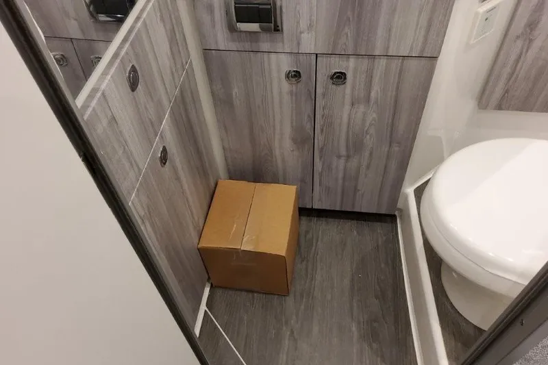 Slide: The Image of Small bathroom with wood paneling and a cardboard box on the floor. - 46