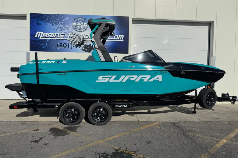 The Image of 2026 Supra SA 575 boat in teal and black on trailer, parked outside. - 0