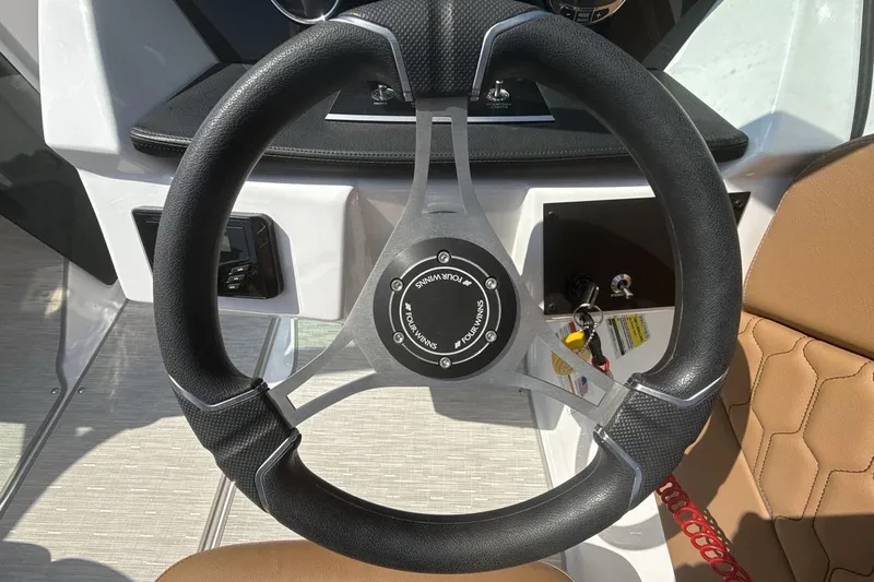 Slide: The Image of Steering wheel of 2024 Four Winns H1 OB boat with modern design and controls. - 14