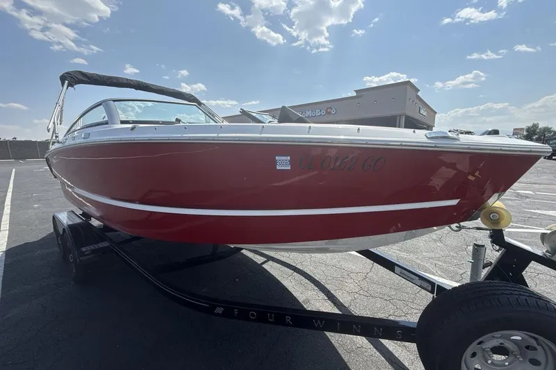 Slide: The Image of 2024 Four Winns H1 OB boat in red on a trailer, parked outdoors. - 7