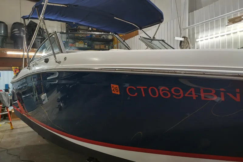 The Image of 2015 Cobalt 24SD boat with blue hull and registration number CT0694BN in a garage. - 0