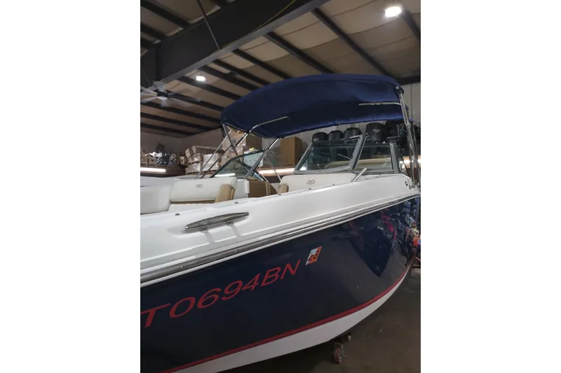 Slide: The Image of 2015 Cobalt 24SD boat with blue canopy in indoor storage. - 2