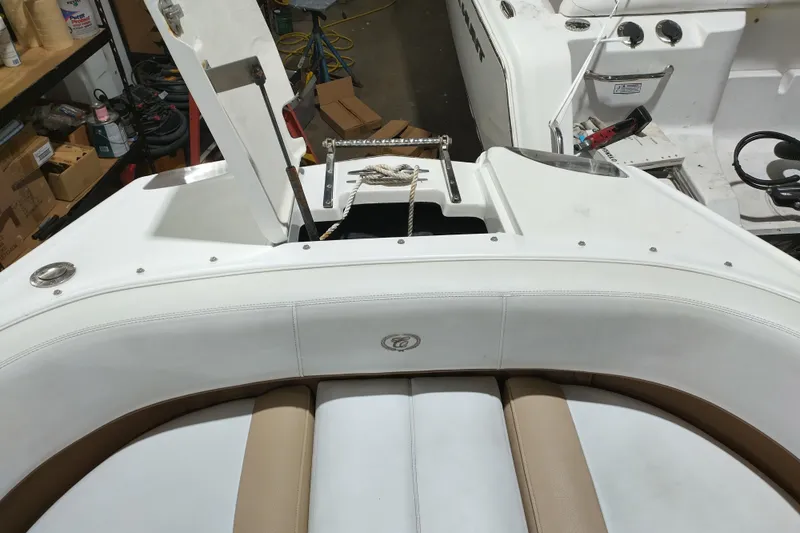 Slide: The Image of 2015 Cobalt 24SD boat interior with white and tan seating, open storage compartment. - 20