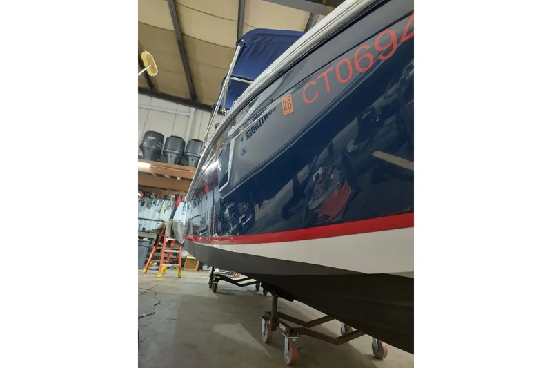 Slide: The Image of 2015 Cobalt 24SD boat in storage, blue hull with red accents, indoor setting. - 3