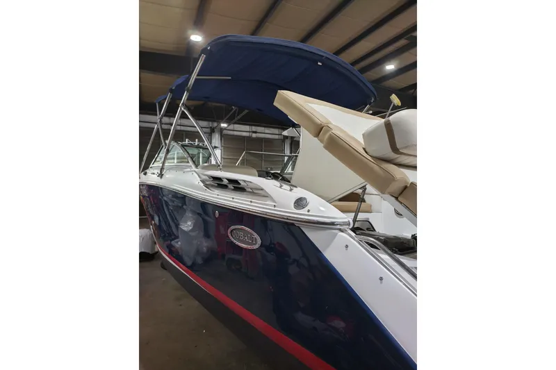 Slide: The Image of 2015 Cobalt 24SD boat with blue hull and canopy in a warehouse. - 4
